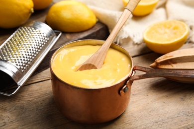 Delicious lemon curd in saucepan on wooden table