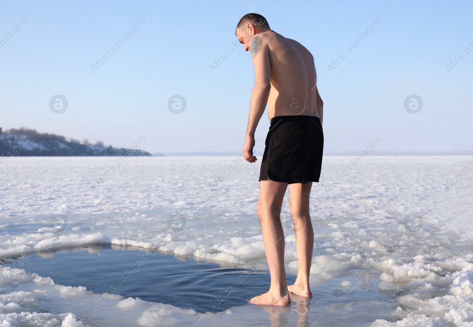 Photo of MYKOLAIV, UKRAINE - JANUARY 06, 2021: Man standing near ice hole on winter day