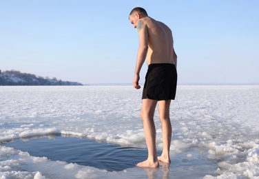 Photo of MYKOLAIV, UKRAINE - JANUARY 06, 2021: Man standing near ice hole on winter day