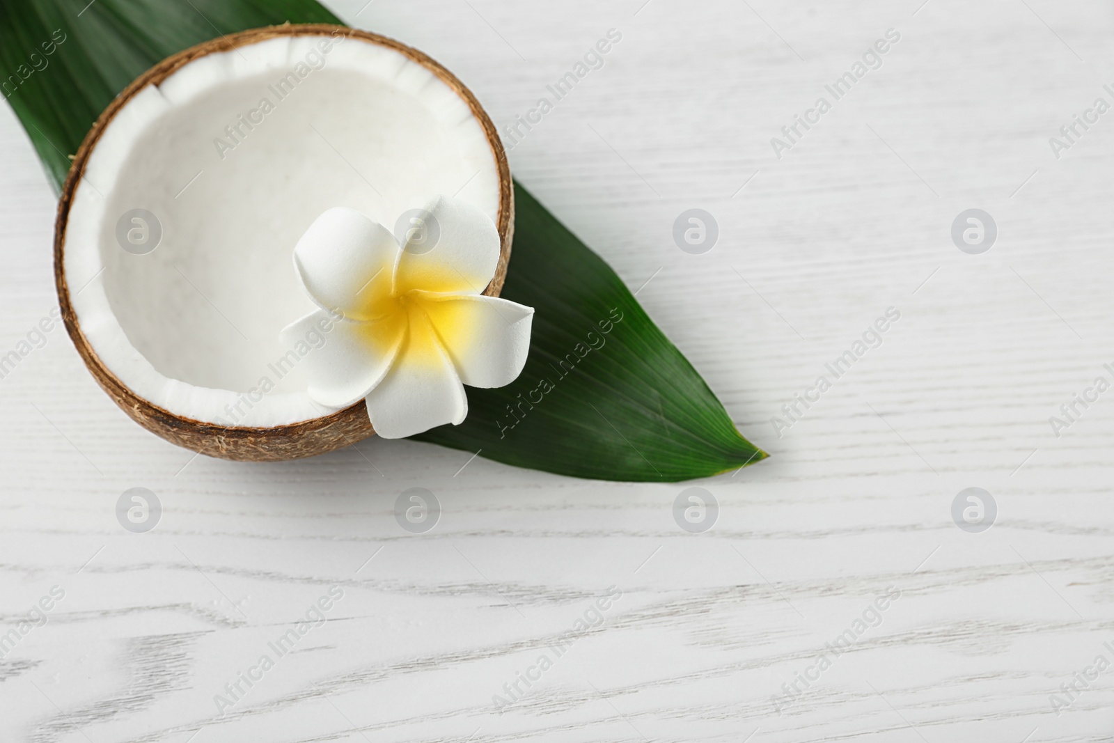 Photo of Composition with half of coconut on white wooden background. Space for text