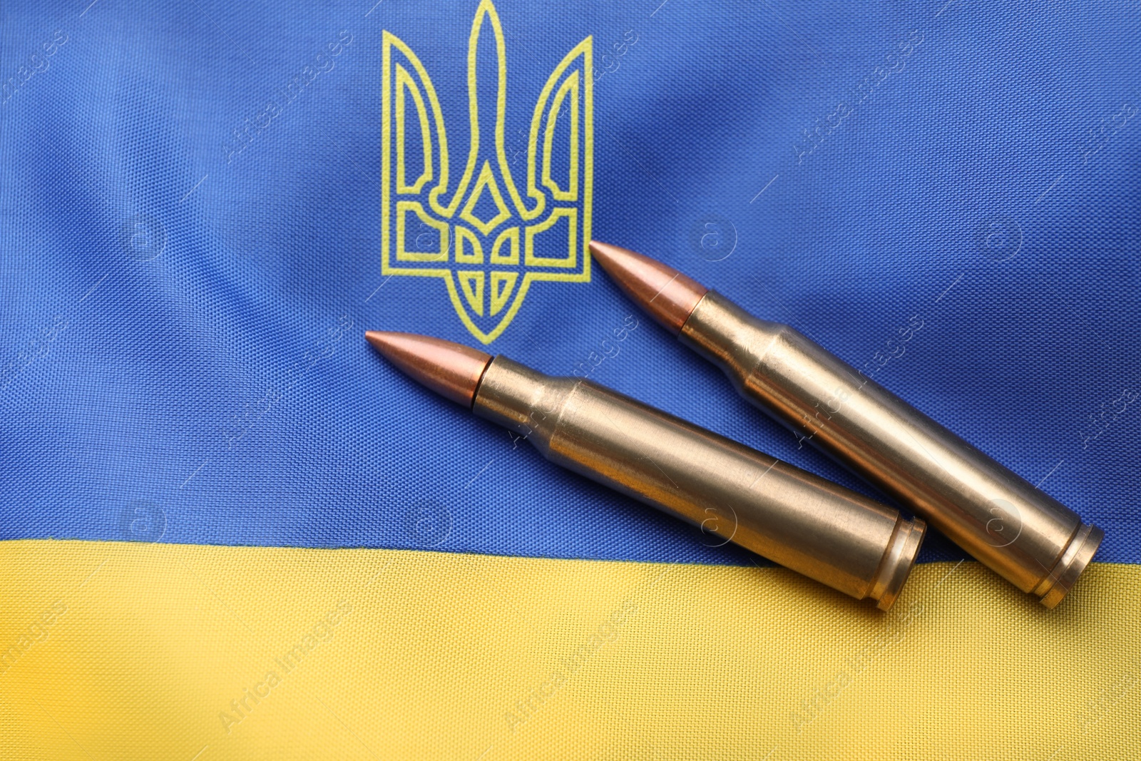 Photo of Military bullets on Ukrainian flag with trident, top view