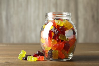 Photo of Delicious gummy bear candies in jar on wooden table