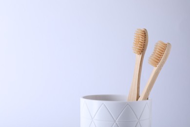 Bamboo toothbrushes in holder on white background, space for text