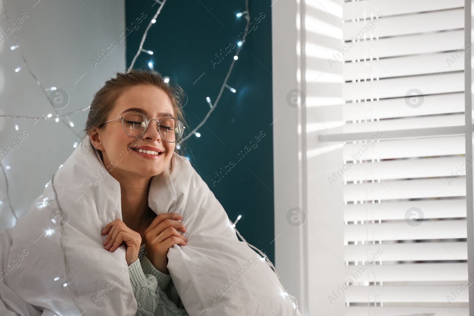 Photo of Young woman wrapped in warm blanket at home. Cozy winter