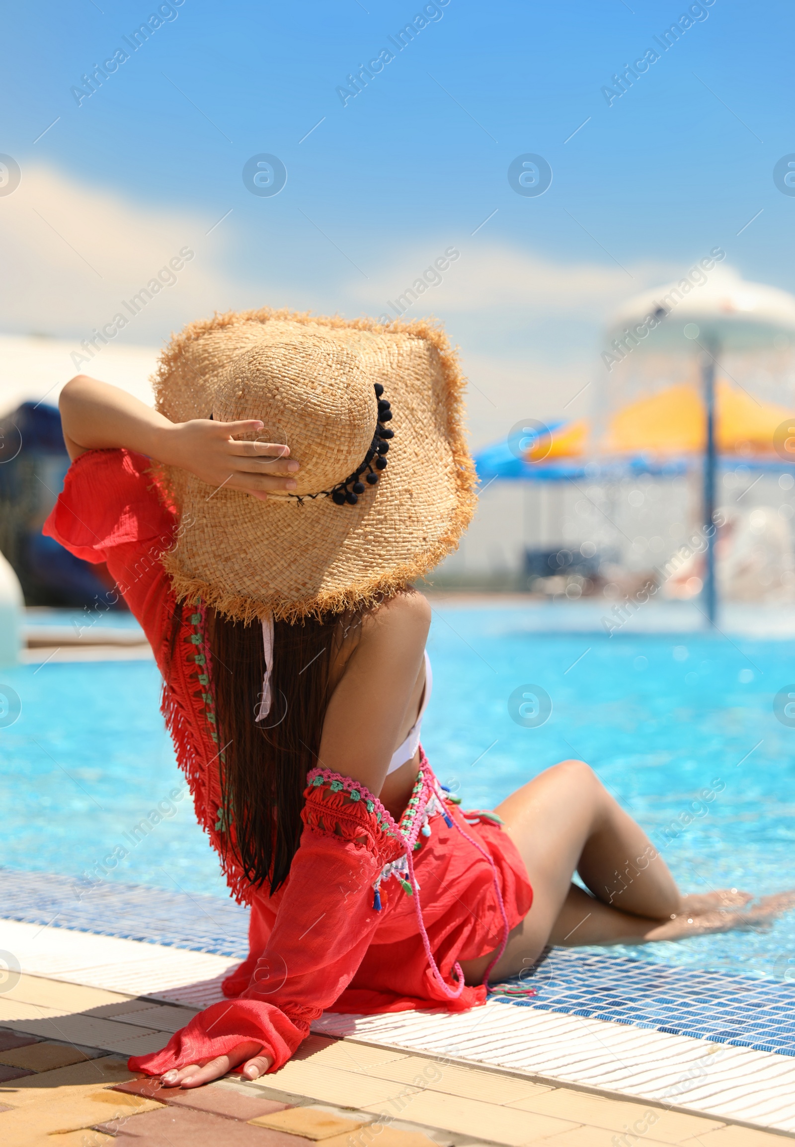 Photo of Young woman sitting near outdoor swimming pool