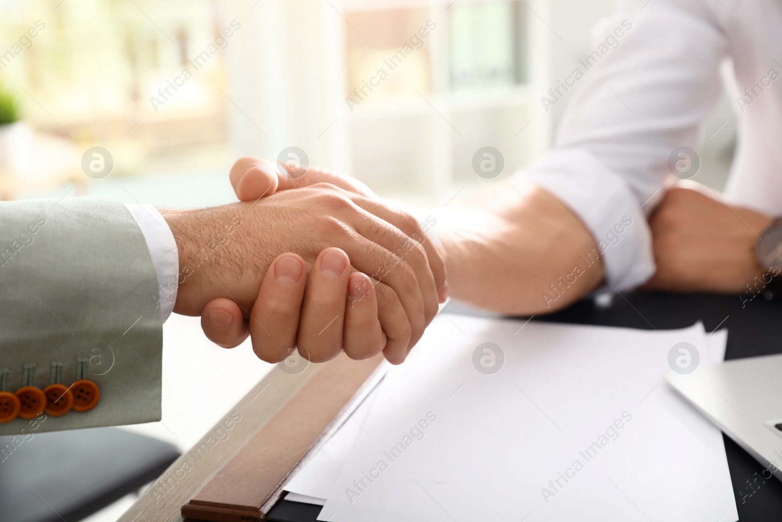 Photo of Business partners shaking hands at table after meeting in office, closeup