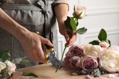 Photo of Florist cutting flower stem with pruner at workplace, closeup