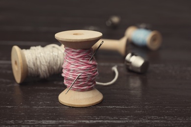 Sewing threads on wooden background
