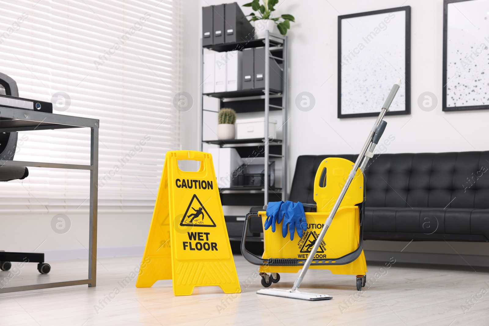 Photo of Cleaning service. Mop, wet floor sign and bucket with supplies in office