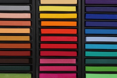 Photo of Set of colorful pastels in trays as background, top view. Drawing materials