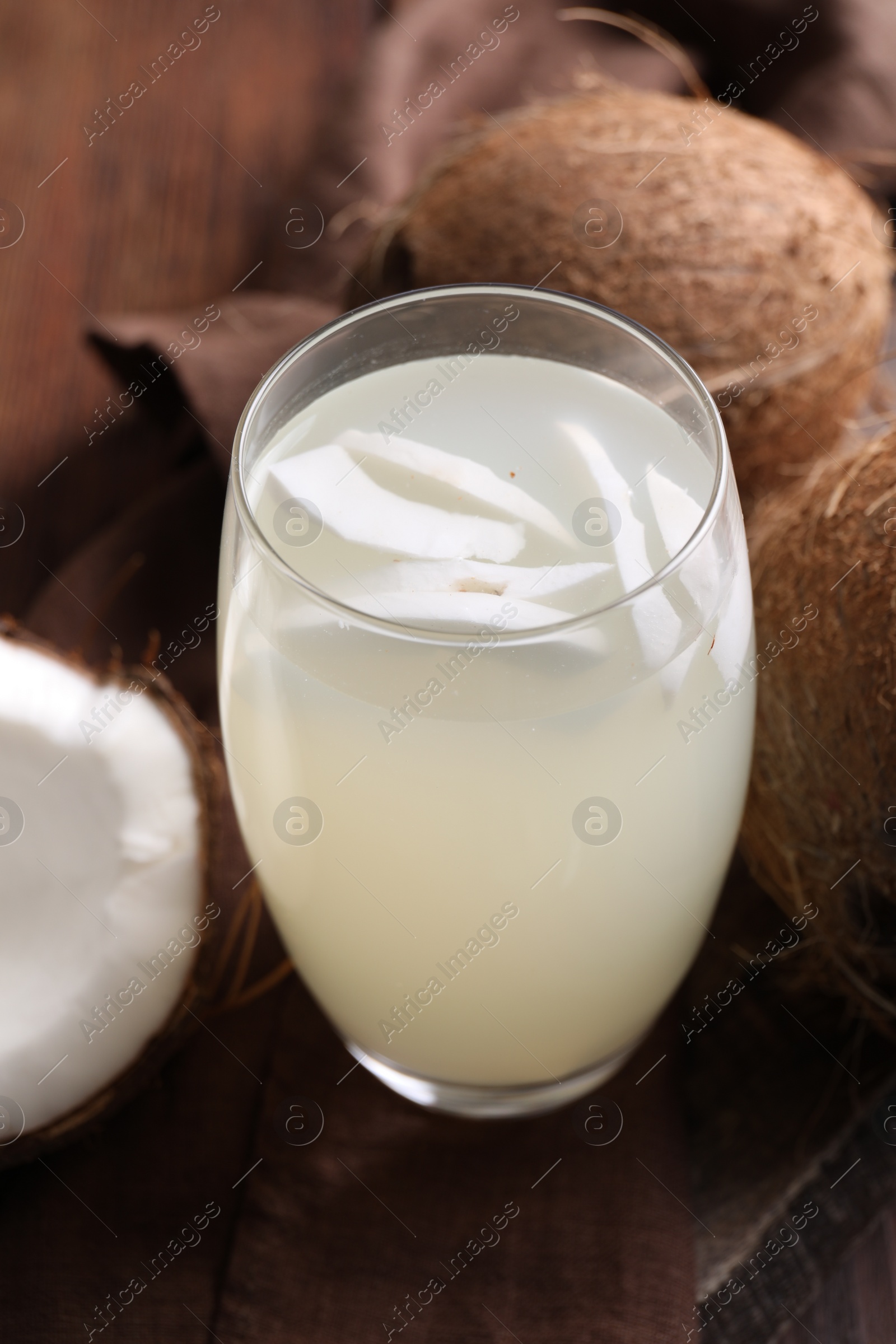 Photo of Glass of coconut water and nuts on wooden table