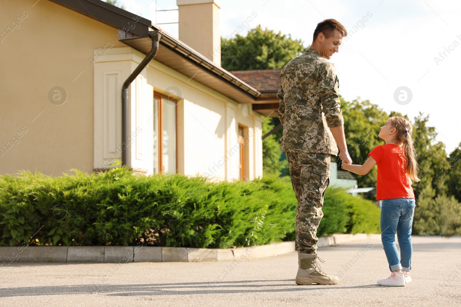 Photo of Father in military uniform with his little daughter outdoors