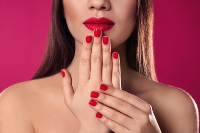 Beautiful woman with stylish nail polish on color background, closeup