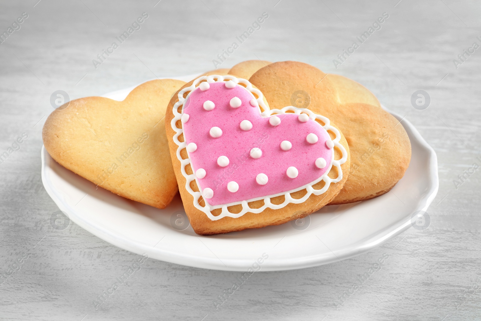 Photo of Plate with decorated heart shaped cookies on wooden table