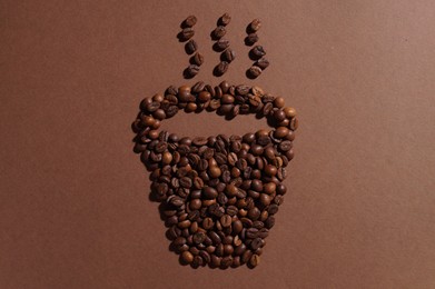 Photo of Cup of hot drink, composition made with coffee beans on brown background, flat lay