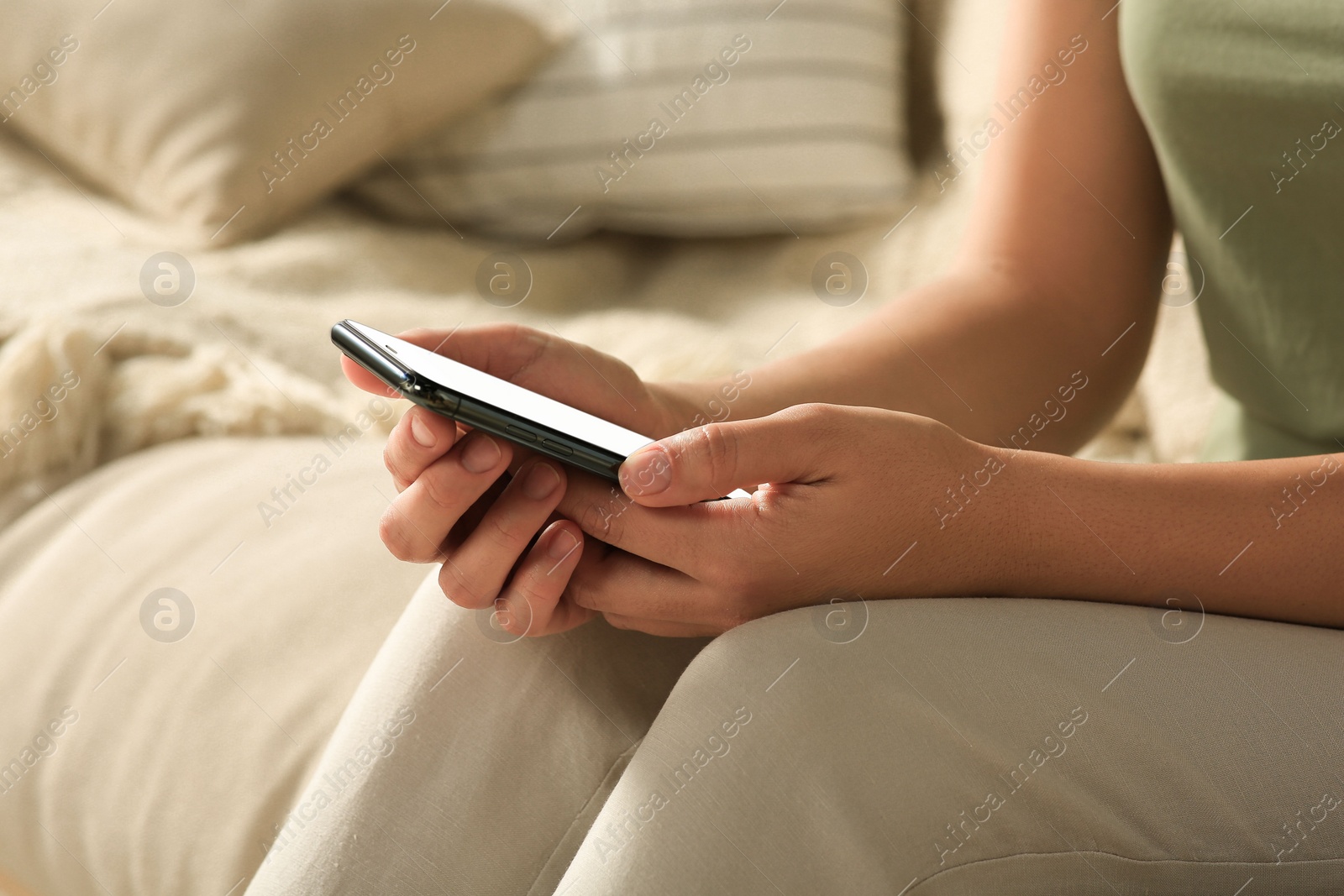 Photo of Woman with smartphone on sofa, closeup view