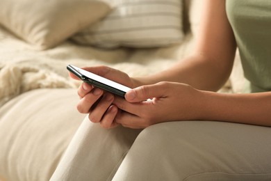 Photo of Woman with smartphone on sofa, closeup view