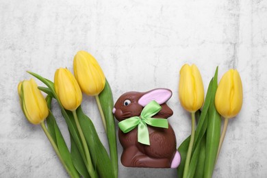 Photo of Flat lay composition with chocolate Easter bunny and beautiful tulips on white textured table