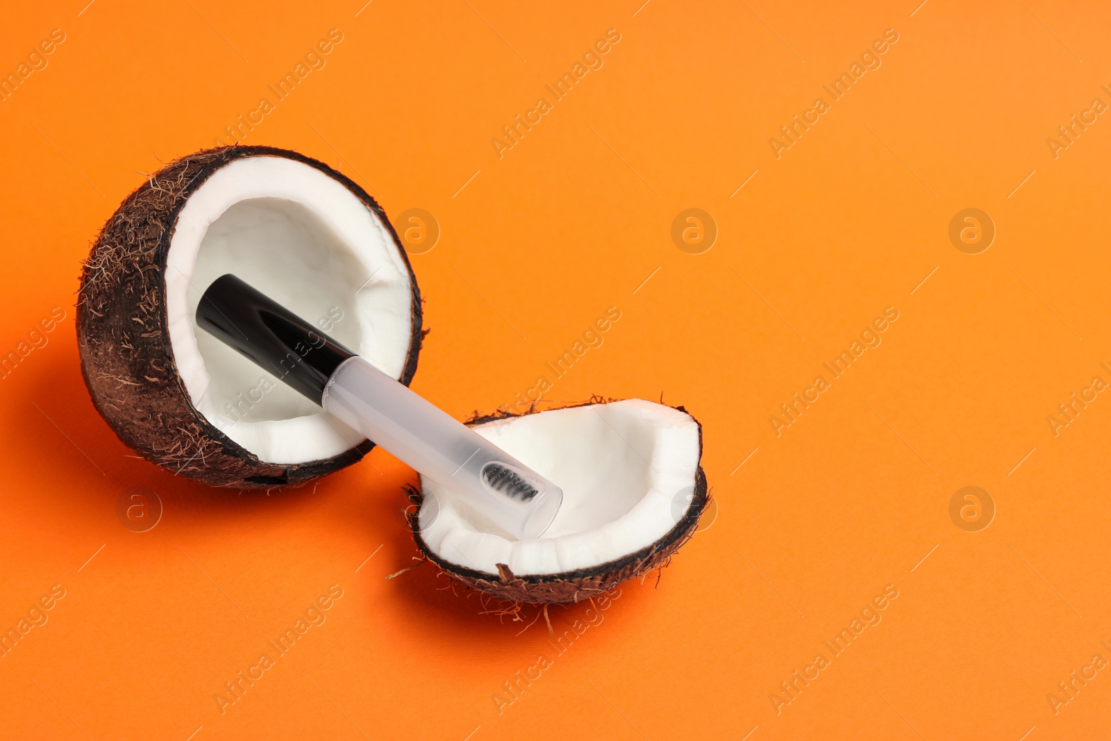 Photo of Tube of eyelash oil and fresh coconut on orange background. Space for text