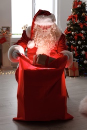 Authentic Santa Claus with bag of gifts indoors