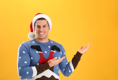 Handsome man wearing Santa hat on yellow background