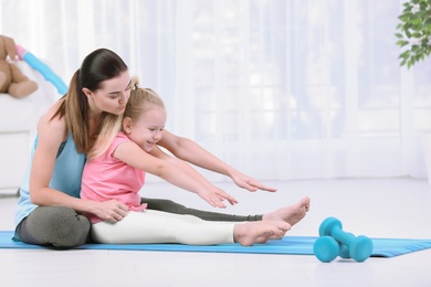 Woman doing fitness exercises with daughter at home