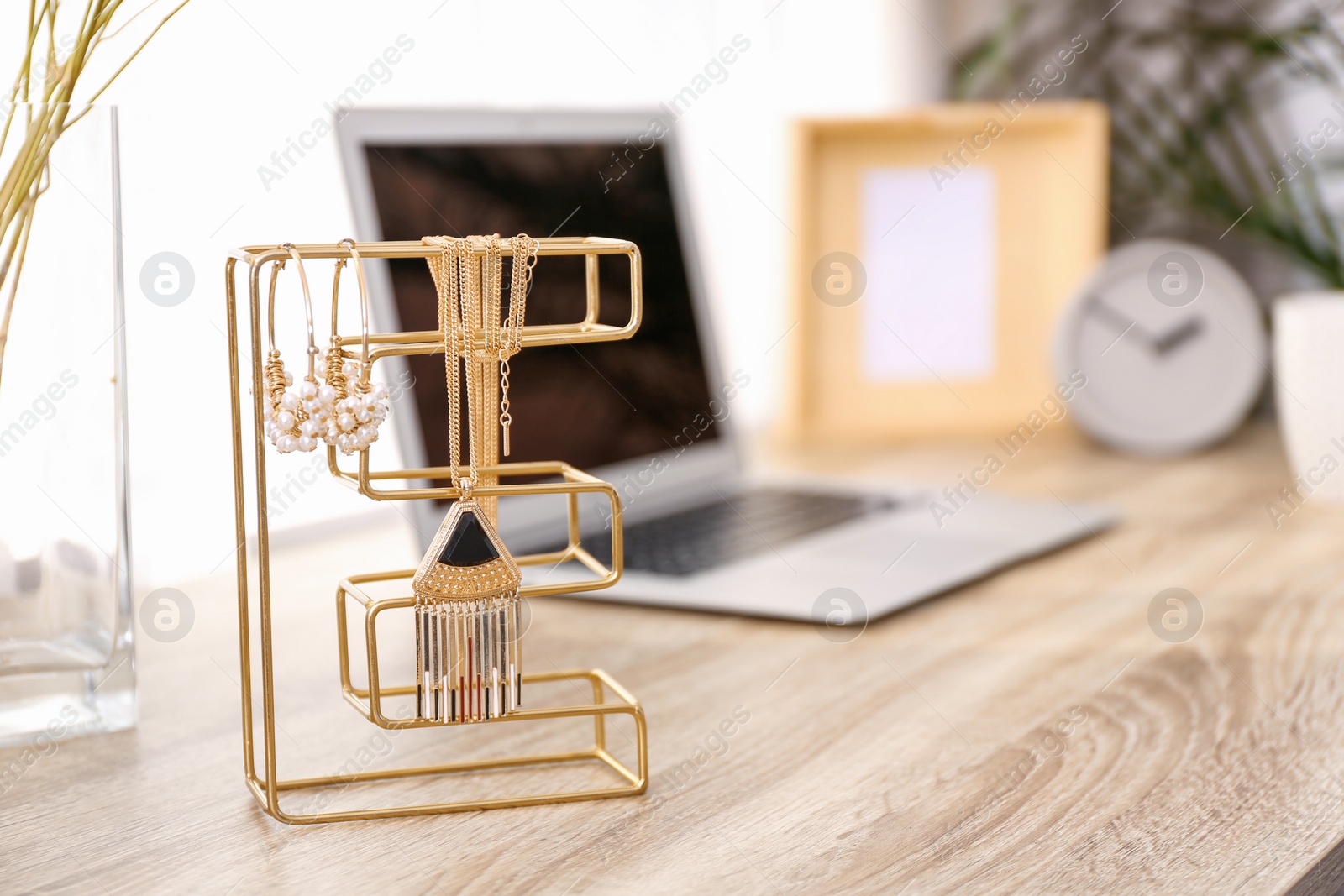 Photo of Stylish workplace interior with jewelry holder on wooden table near window. Space for text