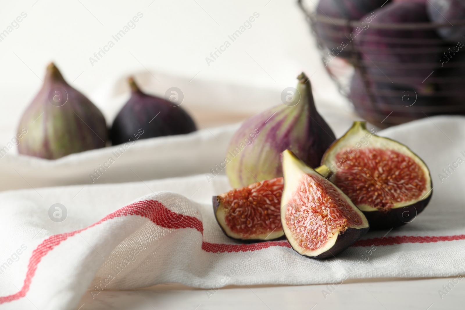 Photo of Tasty cut and whole figs on table with napkin