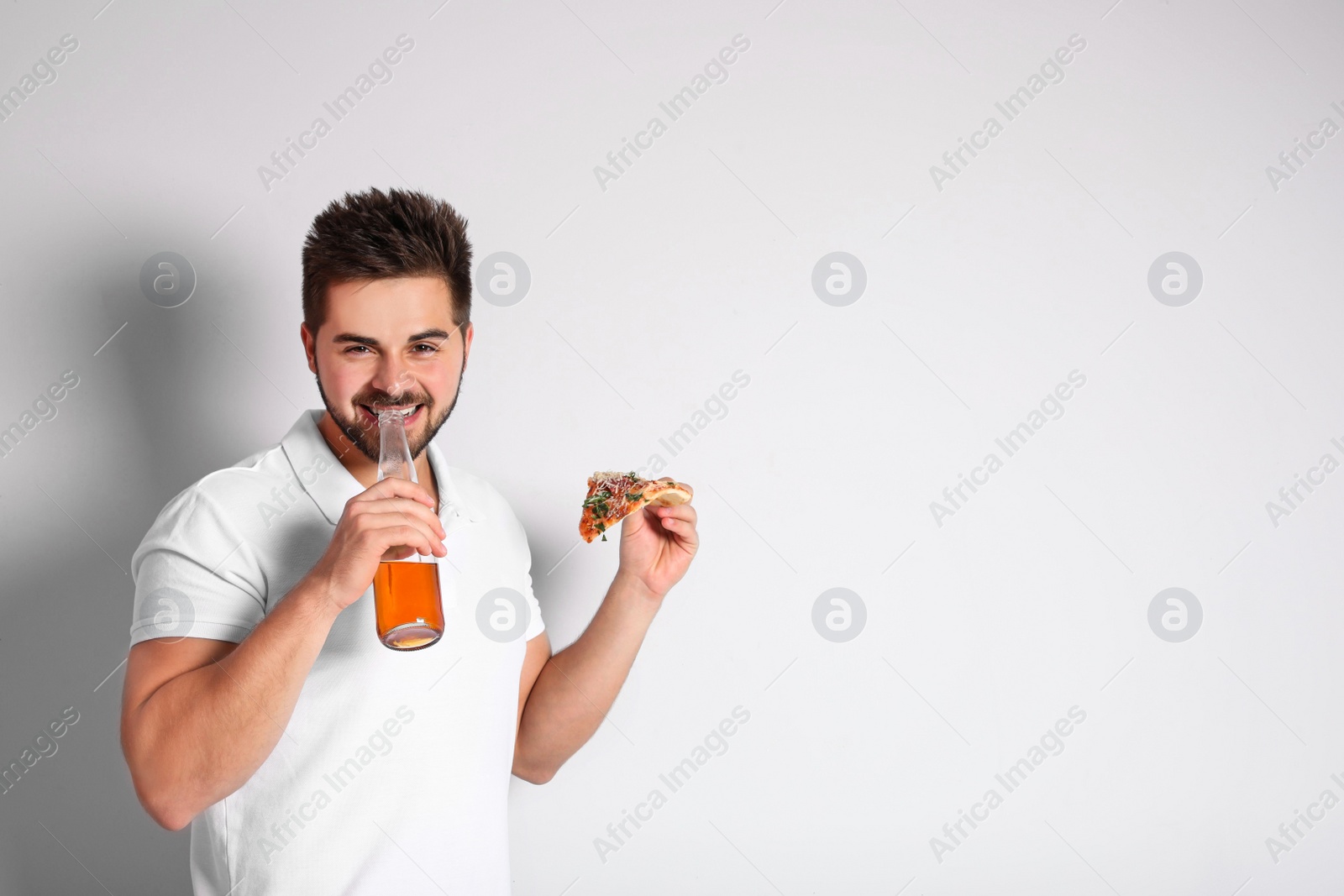 Photo of Handsome man with pizza and beer on white background, space for text