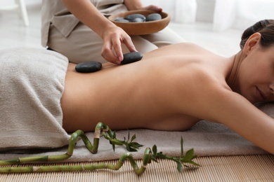 Photo of Beautiful young woman getting hot stone massage in spa salon