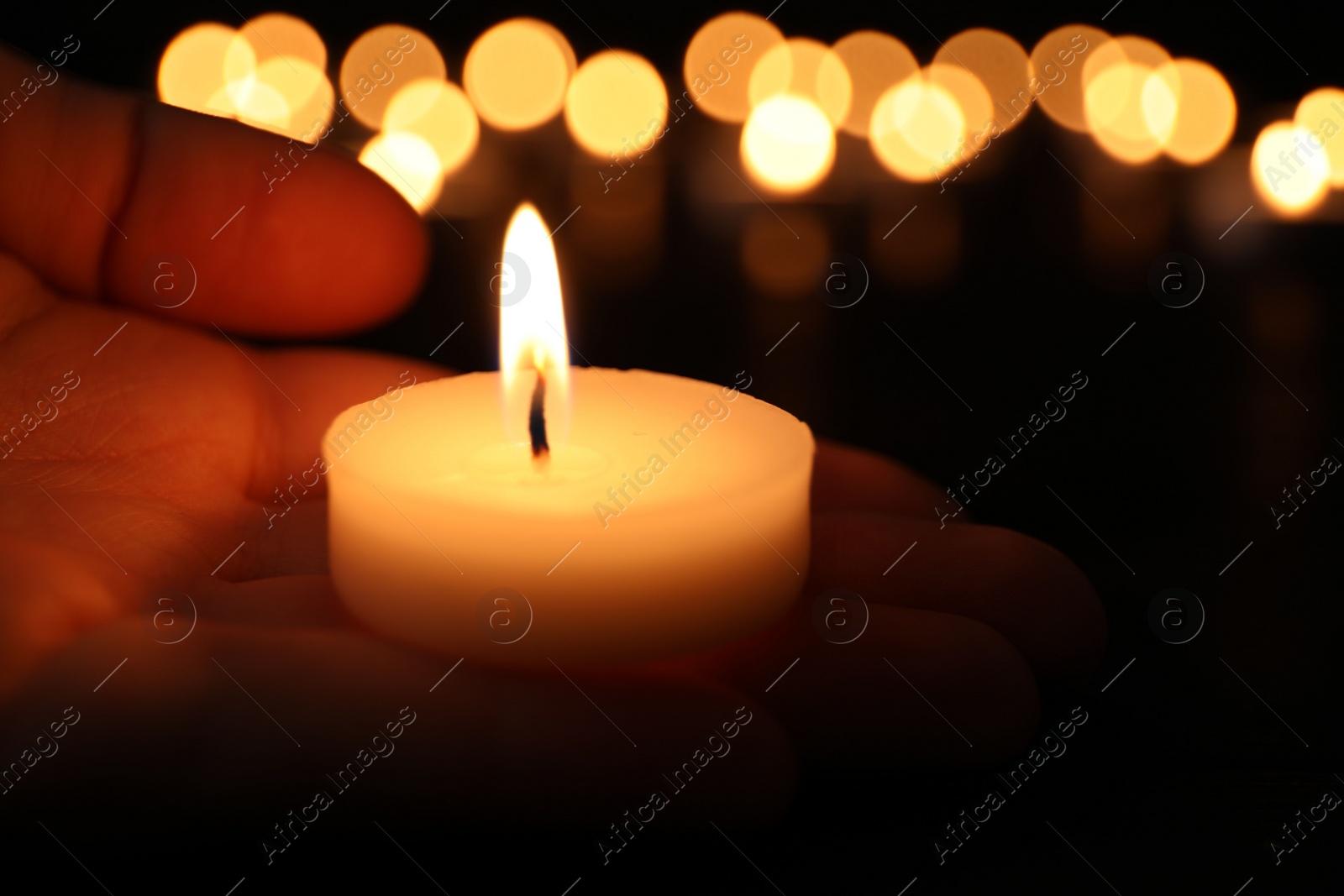 Photo of Woman with burning candle in darkness, closeup. Memory day