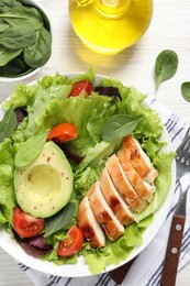 Delicious salad with chicken, cherry tomato and avocado served on white wooden table, flat lay