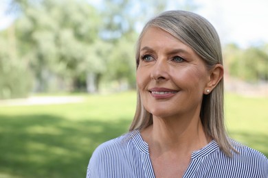 Portrait of beautiful happy senior woman outdoors, space for text