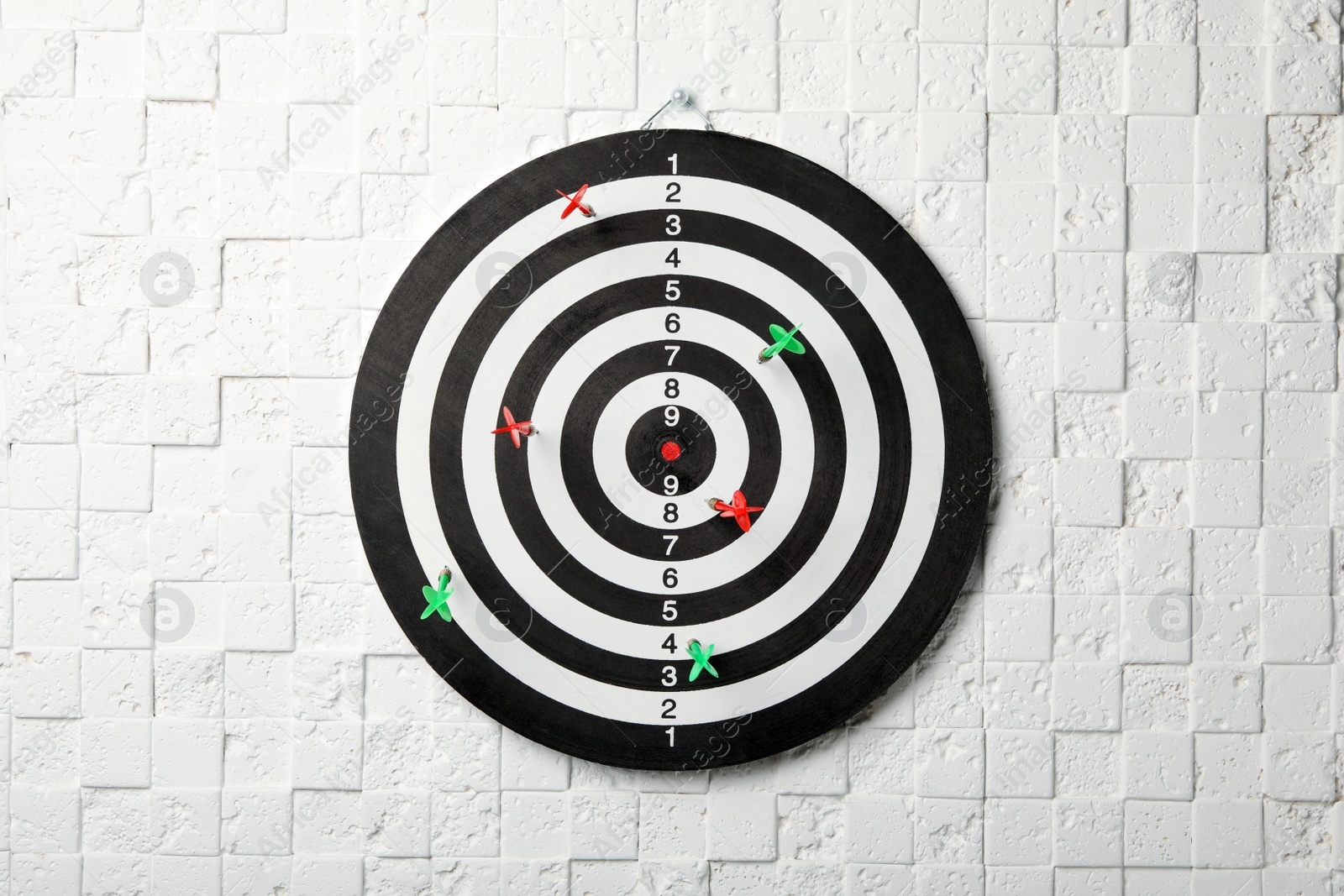 Photo of Arrows hitting dart board on white textured wall