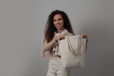 Photo of Happy African-American woman with eco bag on grey background