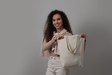 Happy African-American woman with eco bag on grey background