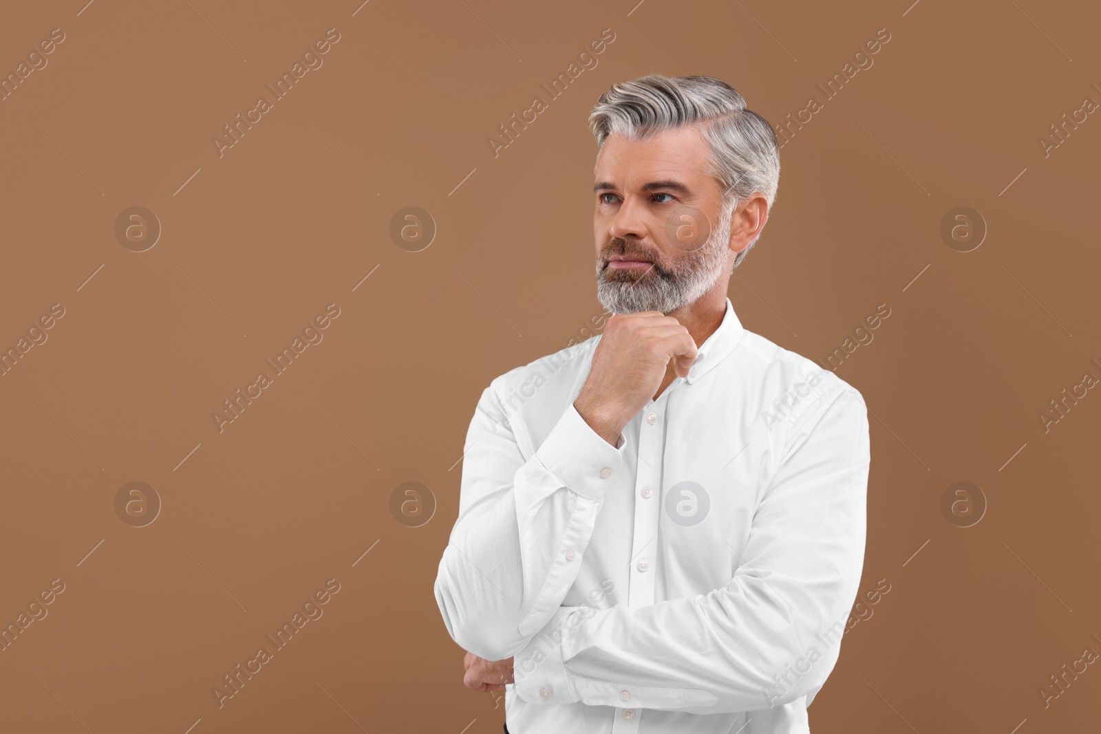 Photo of Portrait of confident man with beautiful hairstyle on light brown background. Space for text