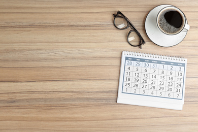 Photo of Flat lay composition with calendar on wooden table. Space for text