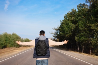 Photo of Man with backpack on road near forest, back view