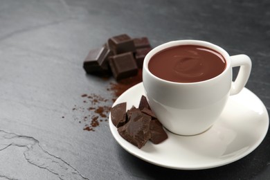 Photo of Yummy hot chocolate in cup on dark table, space for text