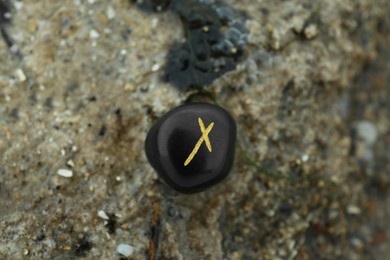 Black rune Nauthiz on stone outdoors, closeup