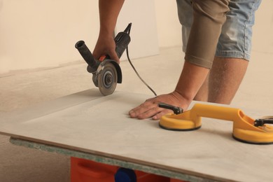 Worker using saw with circular diamond blade for tile cutting indoors, closeup