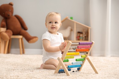 Photo of Children toys. Cute little boy and wooden abacus on rug at home
