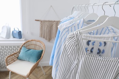 Rack with stylish hanging clothes in dressing room