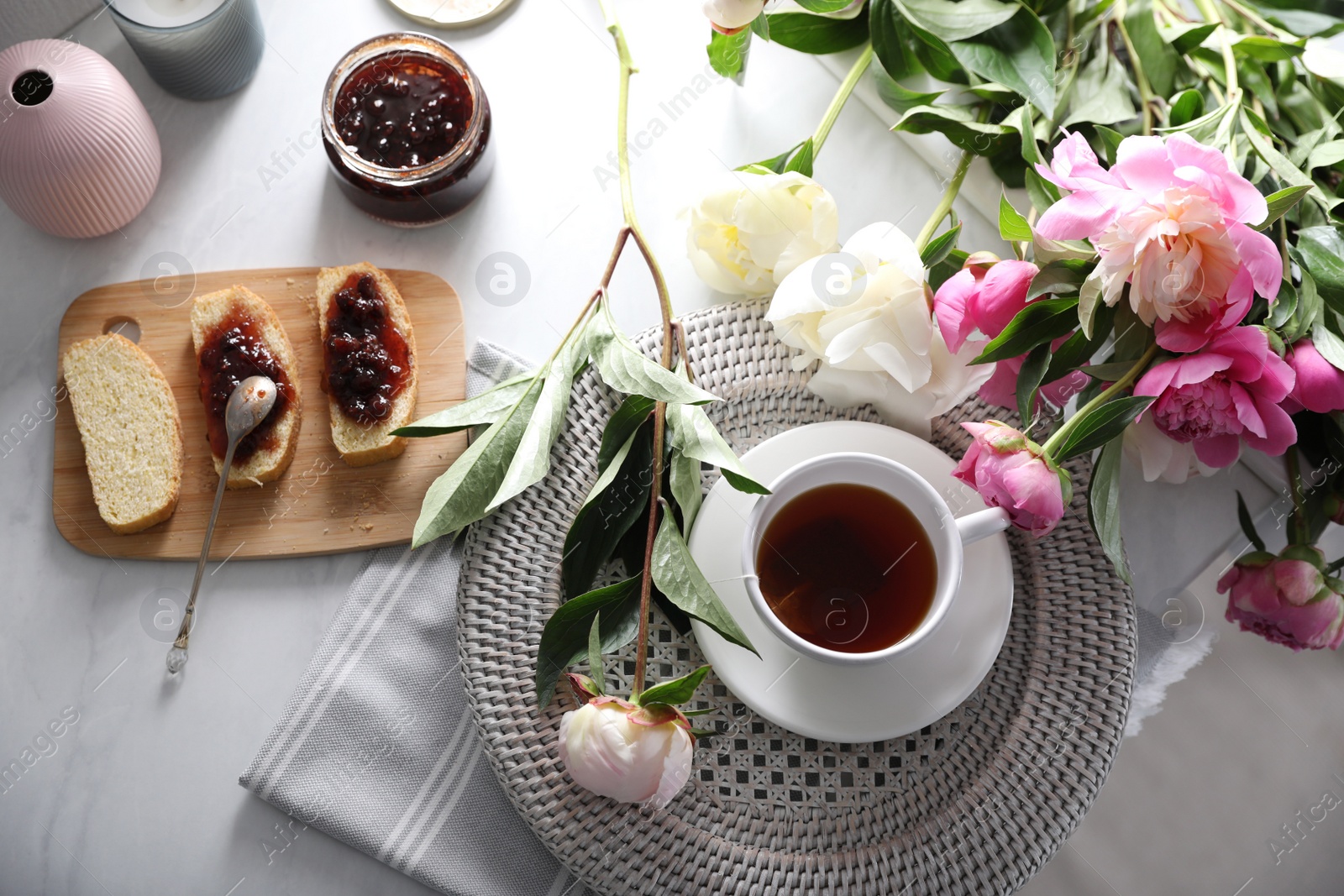 Photo of Beautiful peonies and breakfast on marble table, flat lay