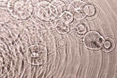 Rippled surface of clear water on beige background, top view