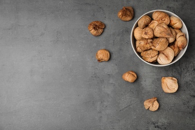 Photo of Bowl of dried figs on grey background, top view with space for text. Healthy fruit