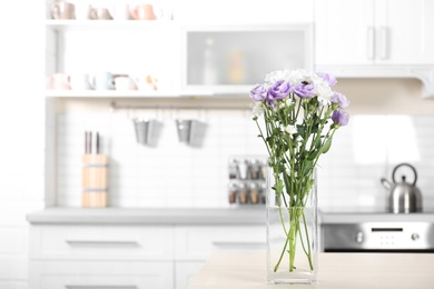 Photo of Vase with beautiful flowers on table in kitchen interior. Space for text