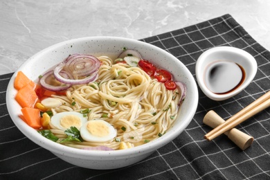 Bowl of noodles with broth, egg, vegetables and chopsticks served on table