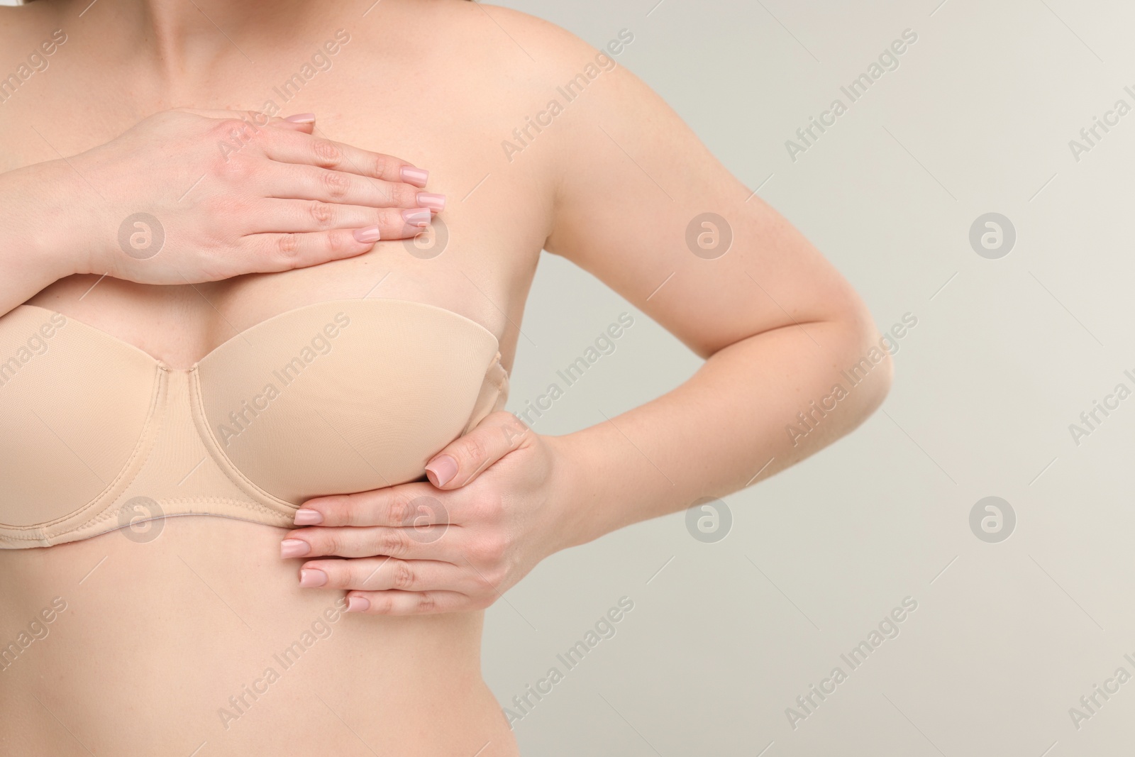 Photo of Mammology. Young woman doing breast self-examination on light grey background, closeup